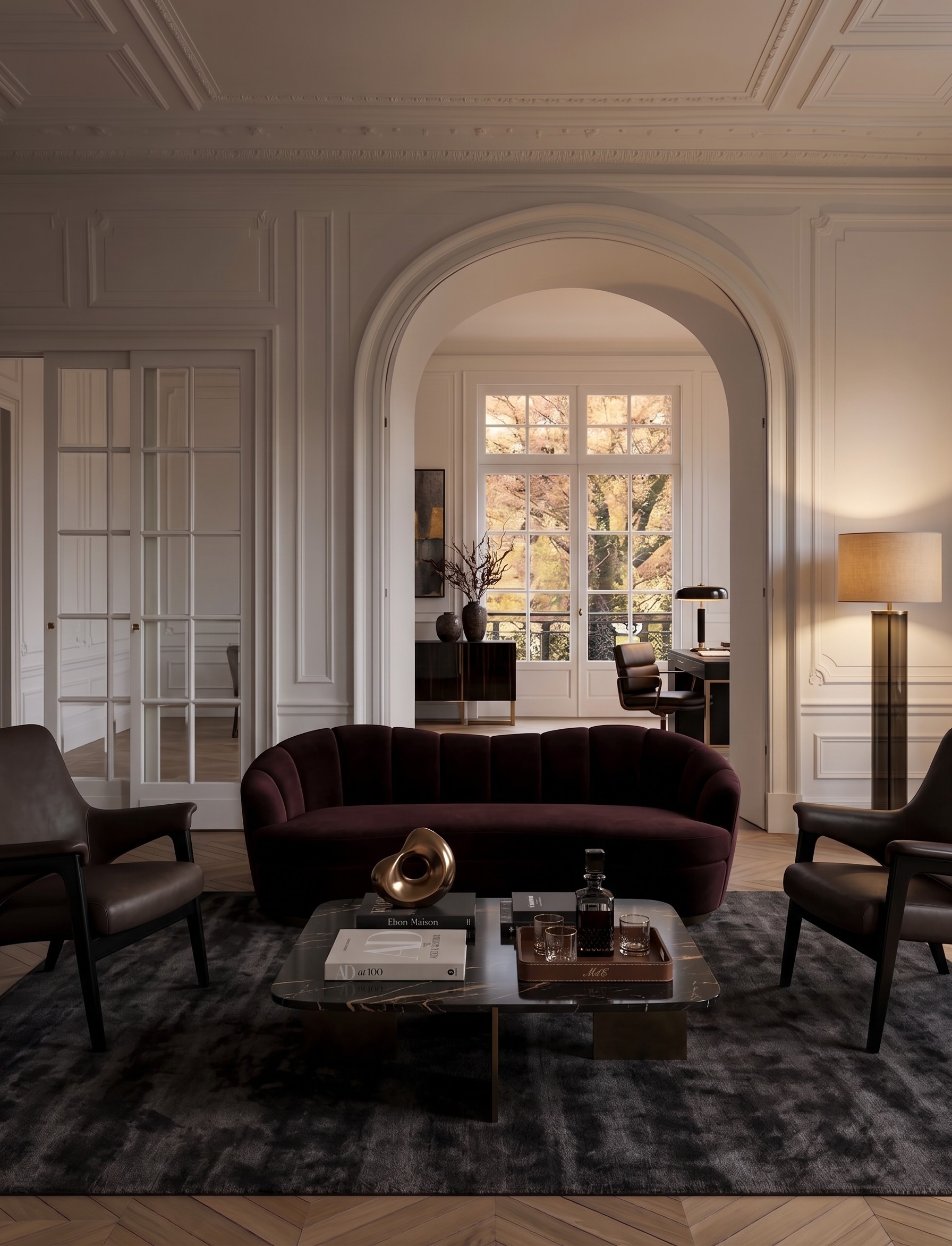 The room curated with a burgundy velvet sofa, leather lounge chairs, marble coffee table and floor lamp